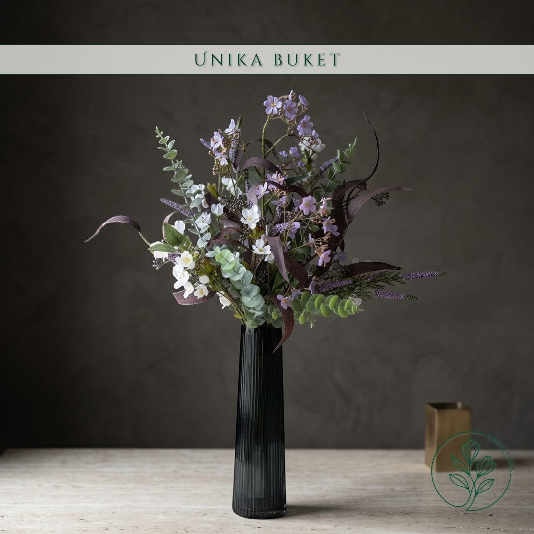 Uniflora buket Sensommerens Eng med vilde markblomster, lilla aks og mørke eukalyptusblade i en sort riflet vase.