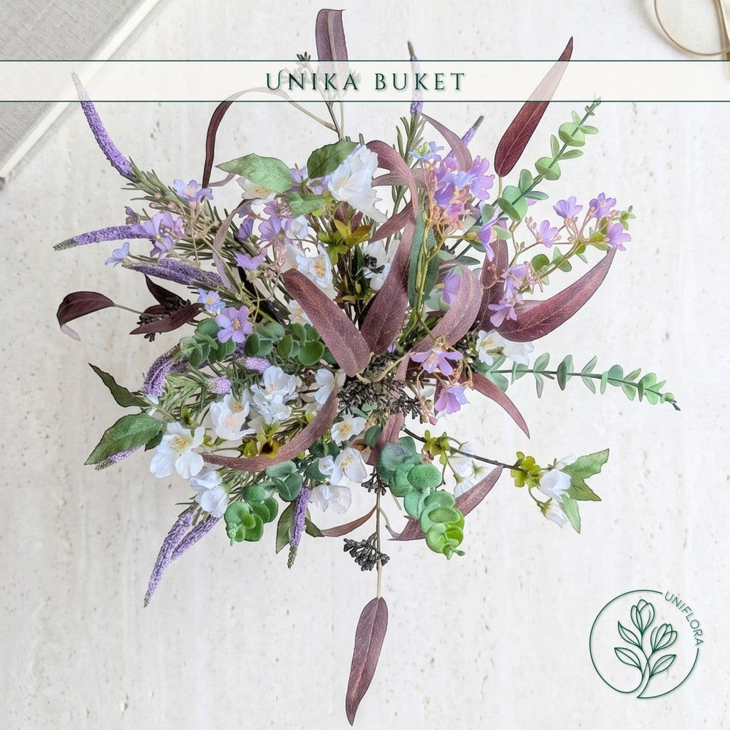 Uniflora buket med vilde markblomster i lilla og hvid samt mørke bordeaux eukalyptusblade i et luftigt design.
