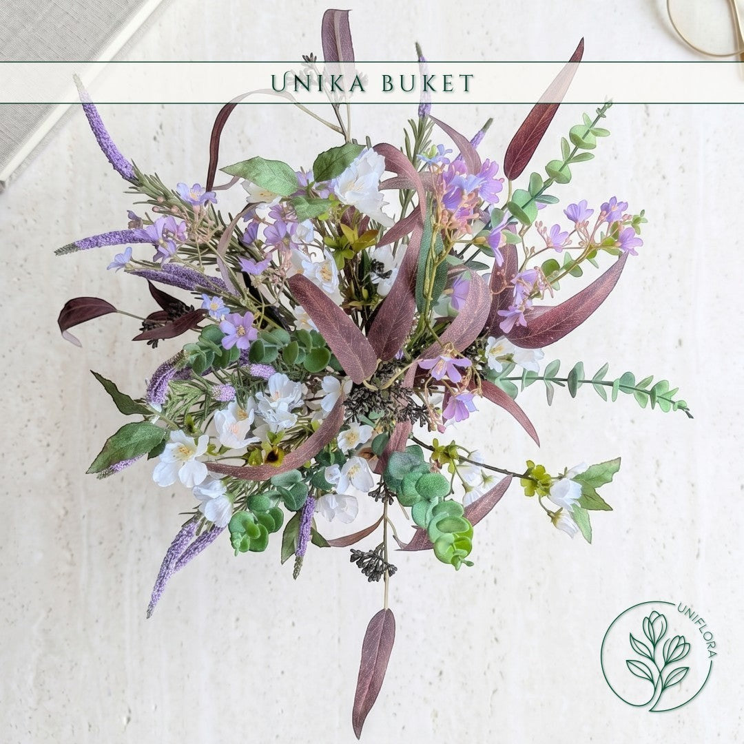 Uniflora buket med vilde markblomster i lilla og hvid samt mørke bordeaux eukalyptusblade i et luftigt design.